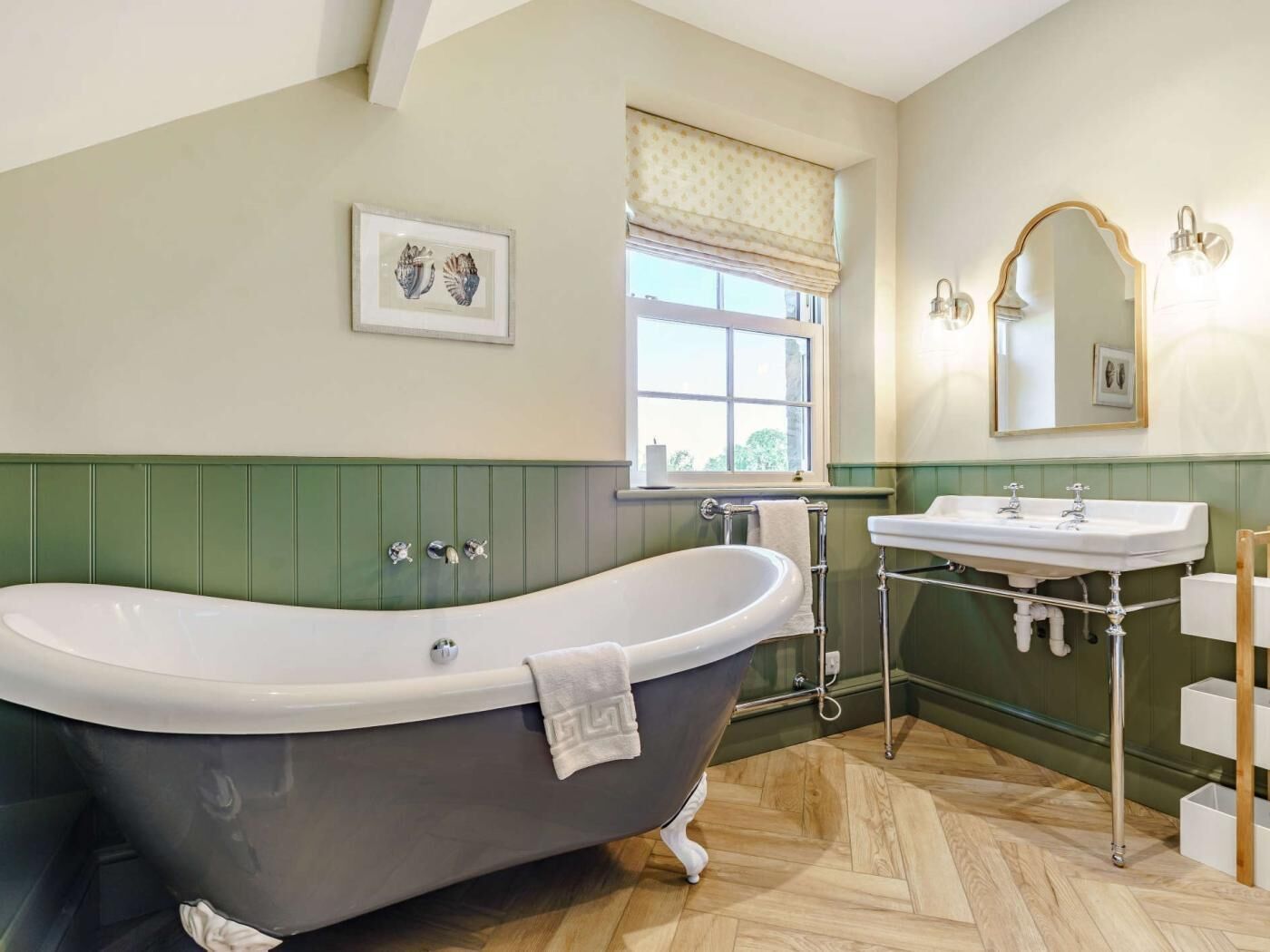 A bathroom with a freestanding bathtub, a vanity with a mirror, and a window with a view.
