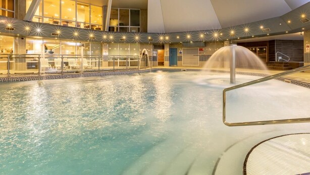 An indoor swimming pool with a fountain, surrounded by a glass enclosure and a modern architectural design. - 2 Bed in Saltash (oc-87706) (Saint Mellion)
