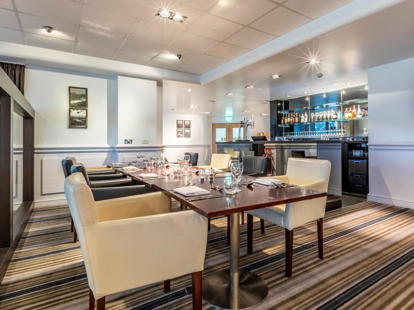 A conference room with a long table, chairs, and a bar area with shelves of bottles.