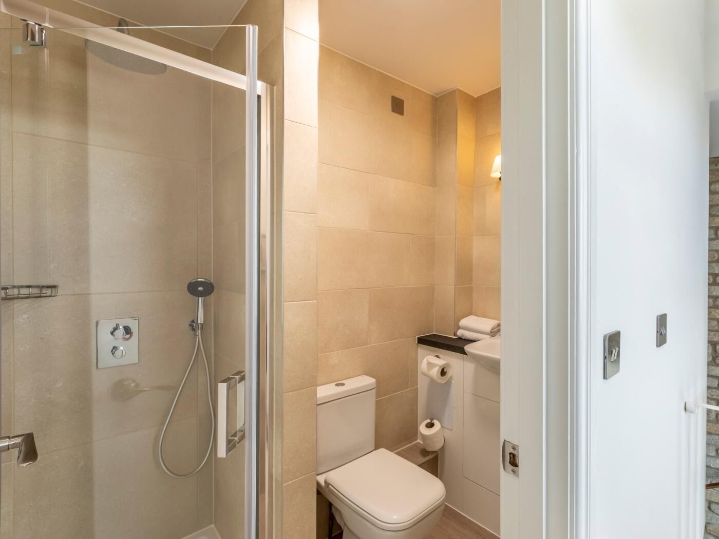 A bathroom with a shower, toilet, and a towel rack.