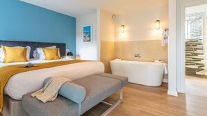 Ett modernt hotellrum med en stor säng, en bänk, ett badkar och en trappa.