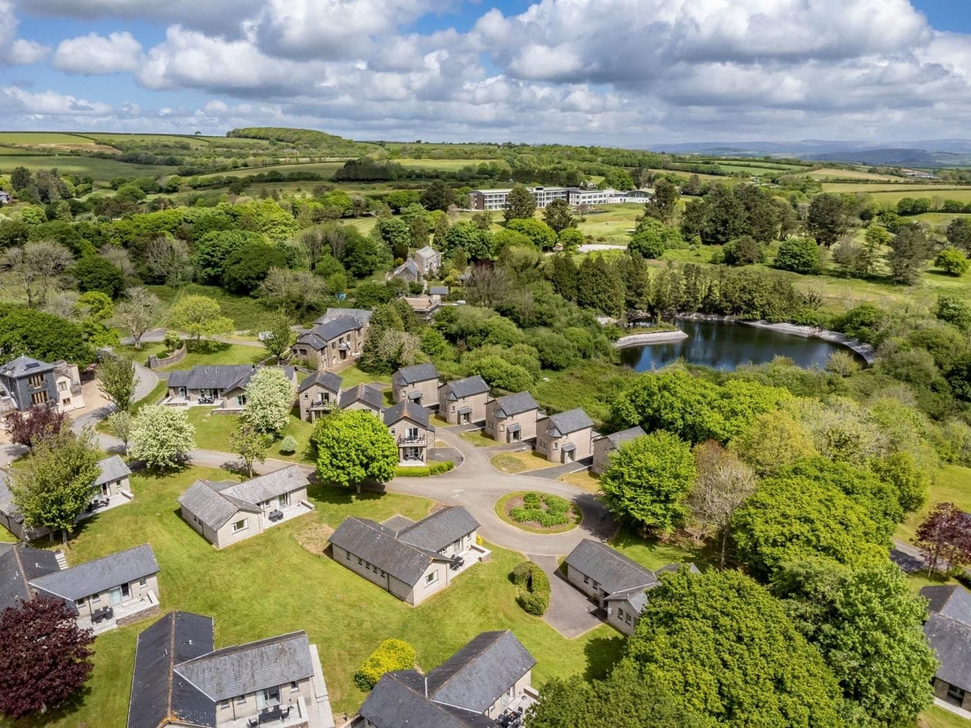 A residential area with houses, a lake, and rolling hills in the background.