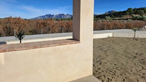 A building with a concrete exterior, a small tree, and a view of mountains and dry vegetation. - Can Mireia Arnes · Els Ports · Free Swimming Pool (Arnes)