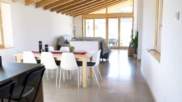 A modern interior with a dining area, white chairs, a wooden table, and a large window.