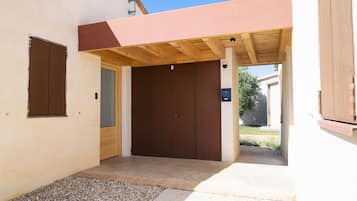 A covered outdoor entrance with a wooden ceiling, a brown door, and a small gravel area.