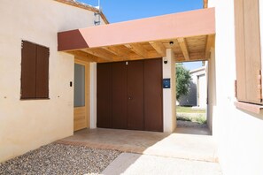 A covered outdoor entrance with a wooden ceiling, a brown door, and a small gravel area.