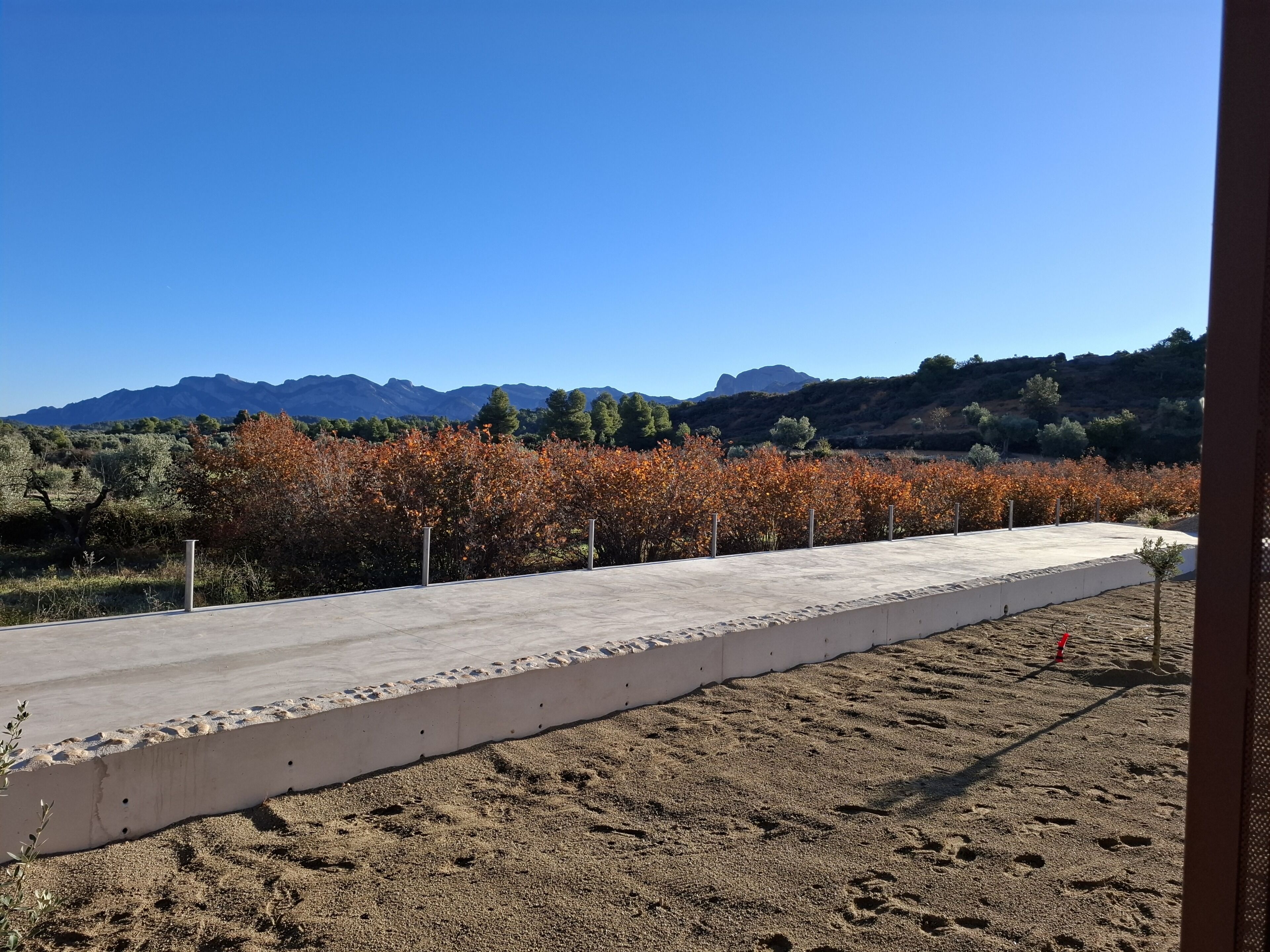 A concrete pathway leading to a building with a view of mountains and autumn foliage.