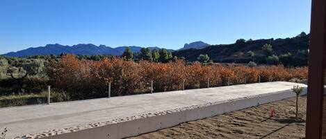 A concrete pathway leading to a building with a view of mountains and autumn foliage.