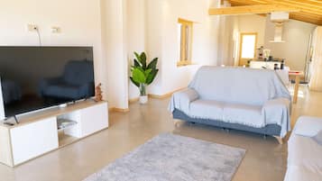 A modern living room with a flat-screen TV, a sofa, a coffee table, and a potted plant.