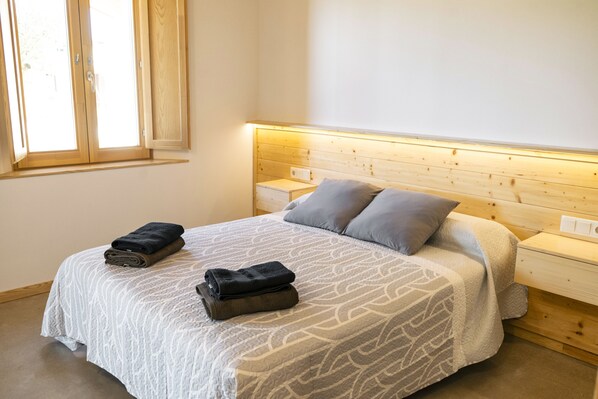 A bedroom with a bed, two bedside tables, a window, and a headboard.
