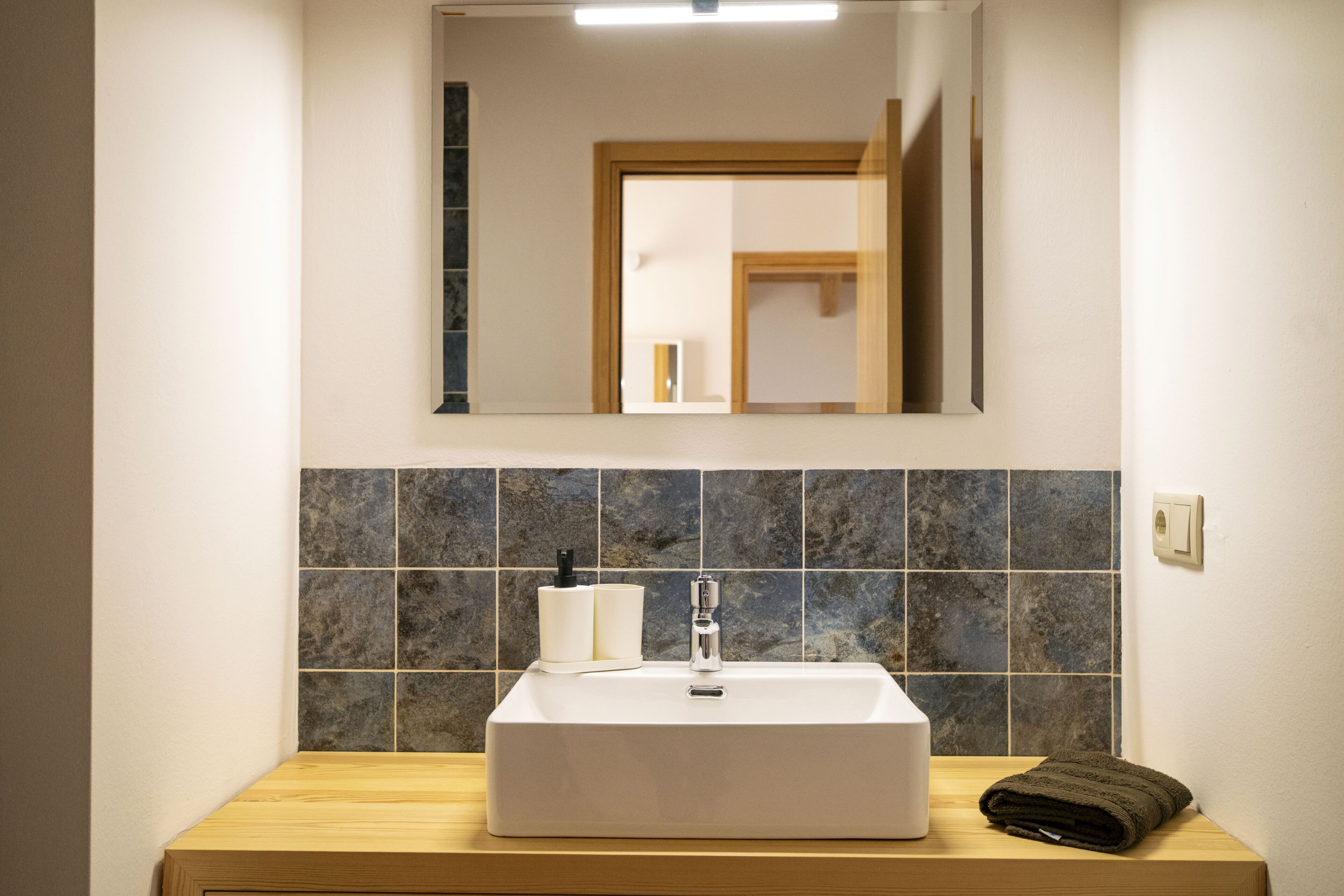 Une salle de bain avec un lavabo blanc, un miroir au-dessus et une serviette posée sur le comptoir.