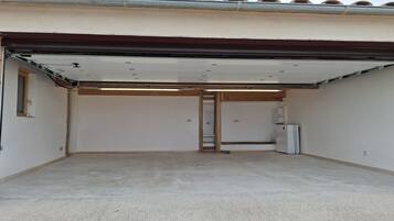 A garage with a concrete floor, a white door, and a metal vent.