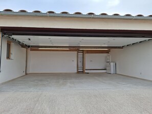 A garage with a concrete floor, a white door, and a metal vent. - Can Mireia · Arnes · Els Ports (Arnes)