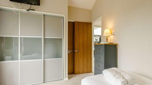 A bedroom with a bed, a wardrobe, a desk with a lamp, and a television on the wall. - 2 Bed in Barnstaple (oc-87360) (Kentisbury)