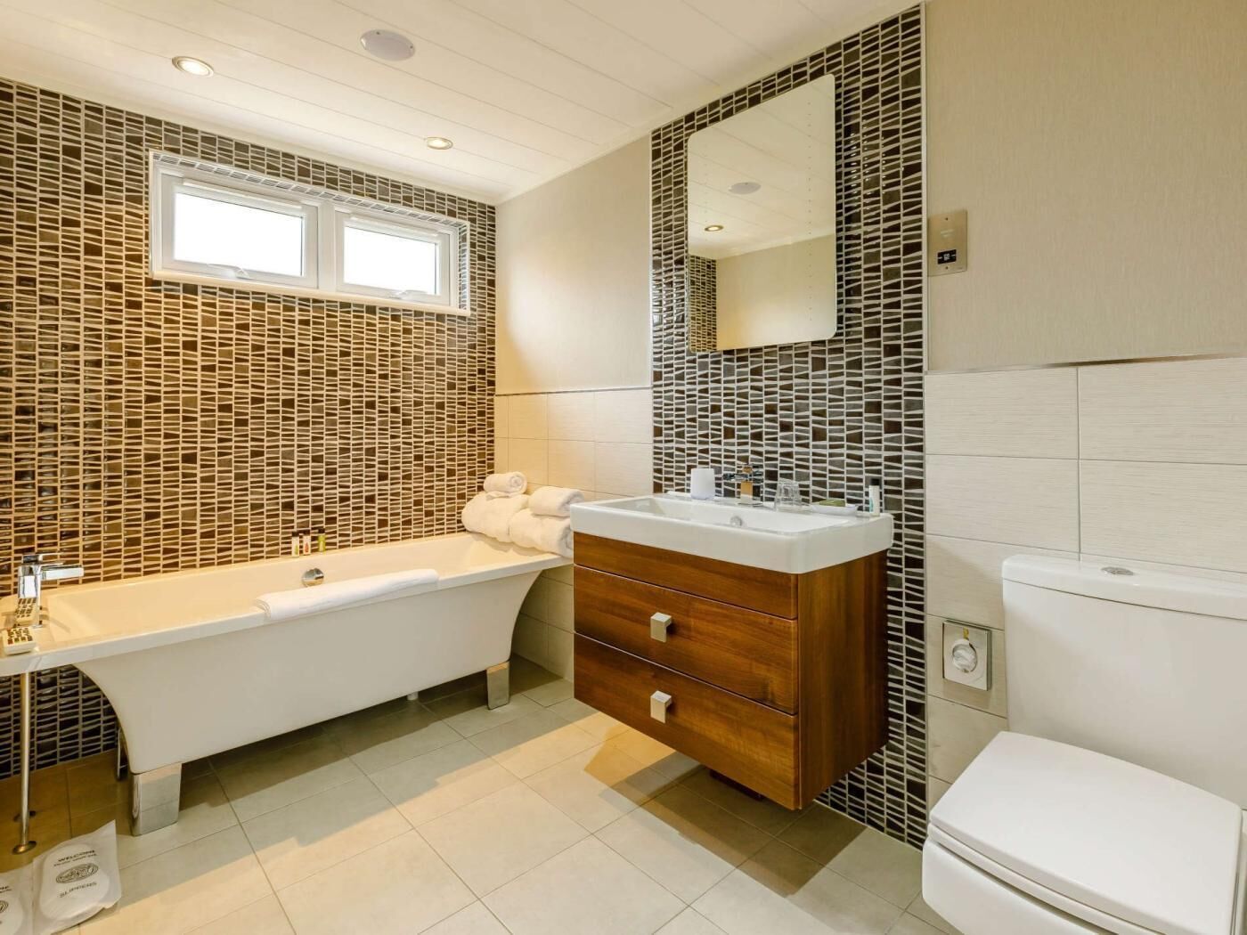 A modern bathroom with a freestanding bathtub, a vanity with a mirror, and a toilet.