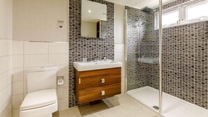 A modern bathroom with a toilet, a vanity with a mirror, and a shower area. - 2 Bed in Barnstaple (oc-87360) (Kentisbury)