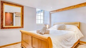 A bedroom with a wooden bed, a large mirror, a window, and a door. - 2 Bed in Morpeth (oc-88270) (Rothbury)