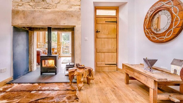 A rustic interior with a stone wall, a wooden door, a fireplace, and a large mirror. - 2 Bed in Morpeth (oc-88270) (Rothbury)