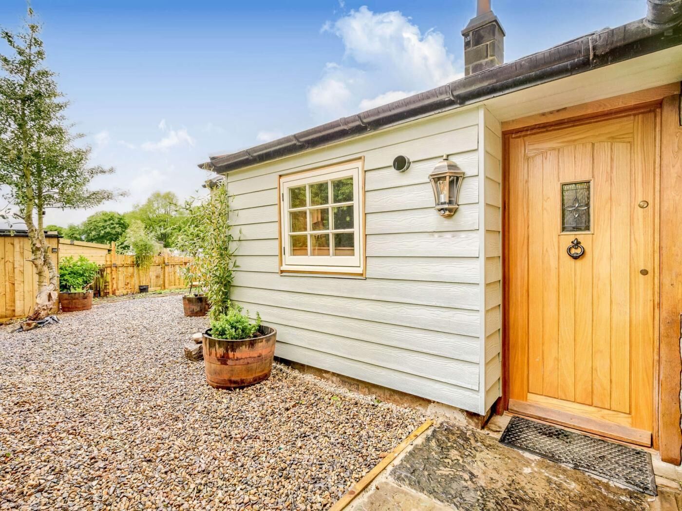 A house with a wooden door, a window, and a small porch area with gravel.