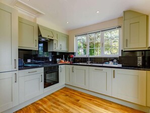 A modern kitchen with white cabinets, a black countertop, and a large window. - 1 Bed in Cinderford (oc-88272) (Cinderford)