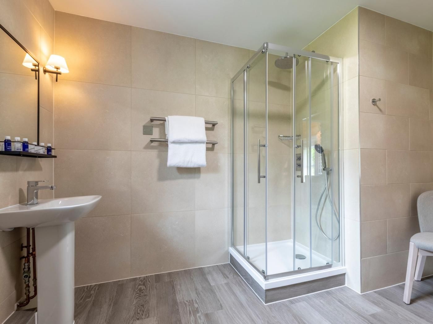 A modern bathroom with a glass-enclosed shower, a white sink, and a towel rack.