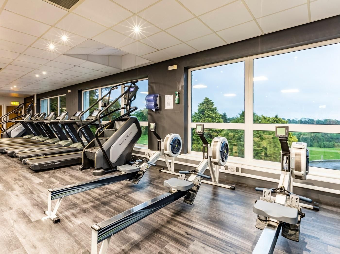 Une salle de sport équipée de tapis de course, de vélos elliptiques et de rameurs.