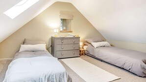 Ein Schlafzimmer mit zwei Betten, einem Schminktisch, einem Nachttisch und einem Oberlicht.
