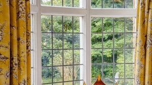 A window with a grid pattern, yellow curtains with floral prints, and three glass vases on the windowsill. - 2 Bed in York (oc-88620) (Londesborough)