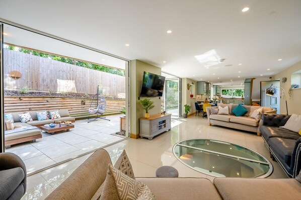 A modern living room with a glass coffee table, sofas, and a television.