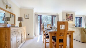 A dining area with a wooden table, chairs, and a sofa. There is a window with curtains, a lamp on the table, and a painting on the wall. - 3 Bed in Ambleside (oc-87524) (Ambleside)