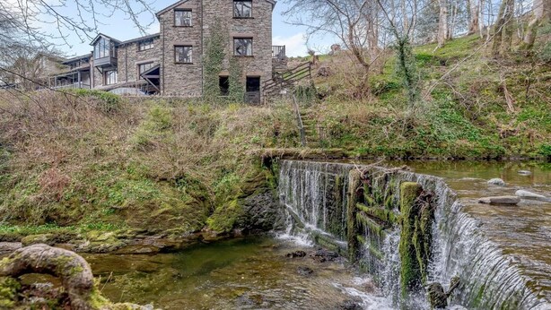 A stone building with multiple windows and a waterfall in the foreground. - 3 Bed in Ambleside (oc-87524) (Ambleside)