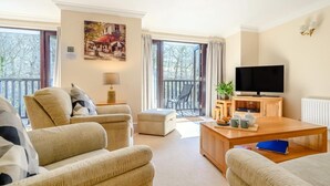 A spacious living room with a sofa set, a coffee table, a TV, and a balcony with a view. - 3 Bed in Ambleside (oc-87524) (Ambleside)