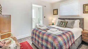 Un dormitorio con una cama, una mesita de noche, una ventana con persianas, una puerta y una alfombra roja.