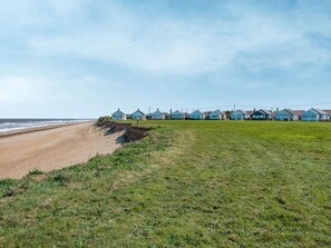Eine Küstenlandschaft mit einer Reihe von blauen Strandhäusern direkt am Strand.