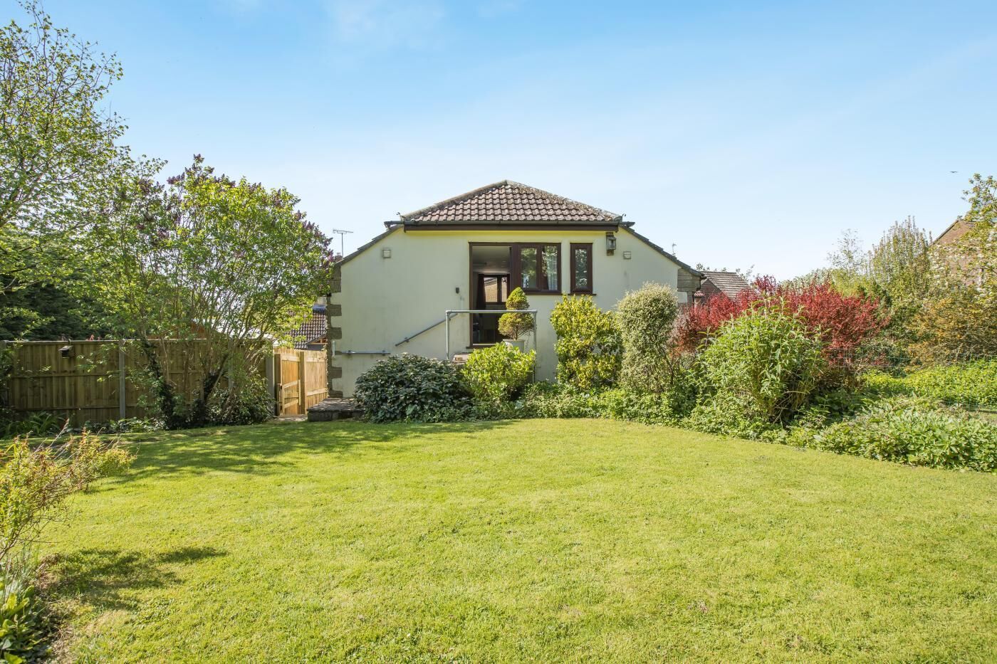 A house with a tiled roof, a front porch, and a well-maintained lawn.