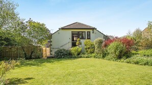 Een huis met een pannendak, een veranda en een verzorgd gazon.