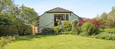 A house with a tiled roof, a front porch, and a well-maintained lawn.