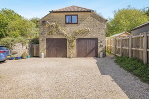 A stone building with two large garage doors, a gravel driveway, and a wooden fence.