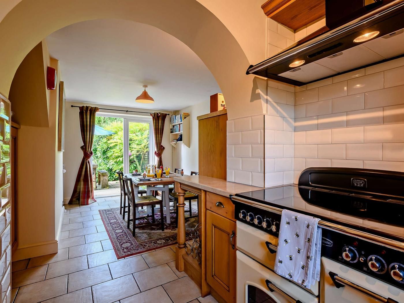 A kitchen with an oven, a stove, and a dining area with a table and chairs.