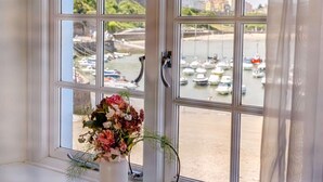 Una finestra con vista sul porto, un vaso di fiori e una maniglia.
