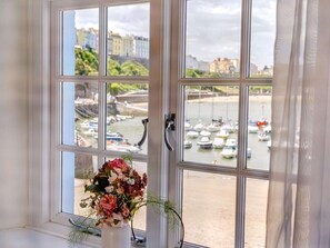 Ein Fenster mit Blick auf einen Hafen, eine Blumenvase und eine Türgriff.