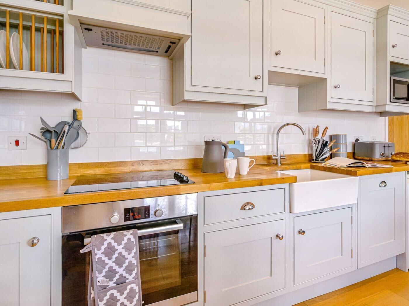 A kitchen with white cabinets, a wooden countertop, a stainless steel oven, and a microwave.