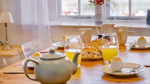 Una tavola imbandita per la colazione con tè, caffè, pasticcini e succo d'arancia.