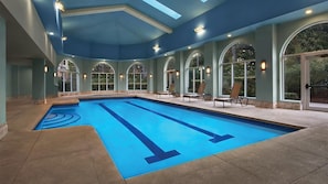 An indoor swimming pool with clear blue water, surrounded by arched windows and lounge chairs. - Family-friendly, 2-bedroom condo with lots of amenities right on the beach. (Myrtle Beach)