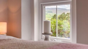 Ein Schlafzimmer mit großem Fenster, Nachttisch und Lampe.