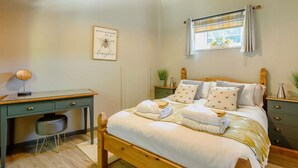 Un dormitorio con cama de madera, mesitas de noche, un escritorio y una ventana con cortinas.