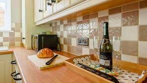 Una cocina con una hogaza de pan, una botella de vino y una tabla de cortar sobre la encimera.