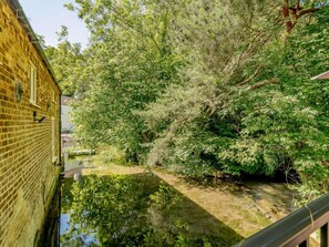 A narrow waterway with dense foliage on one side and a brick building on the other. - 2 Bed in Louth (oc-88629) (Legbourne)