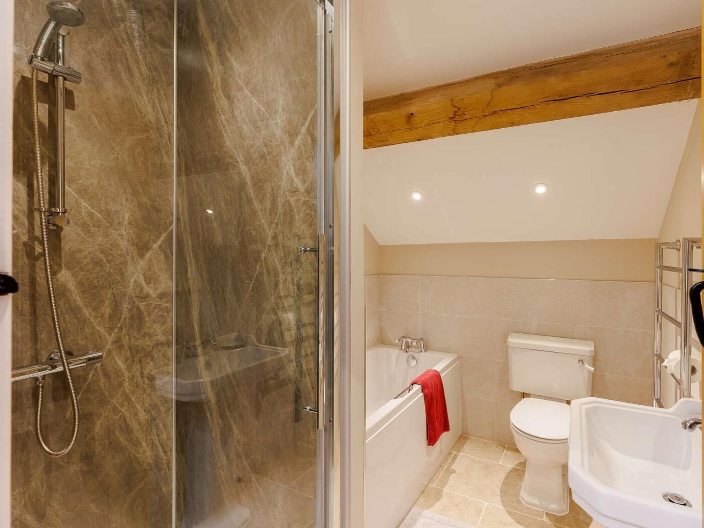 A bathroom with a glass-enclosed shower, a bathtub, a toilet, and a sink.