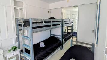 Een slaapkamer met een stapelbed, een bureau en een garderobe.